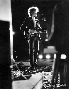 a man in a suit and tie playing an electric guitar