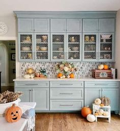 a kitchen with blue cabinets and pumpkins on the counter top, along with other decorations