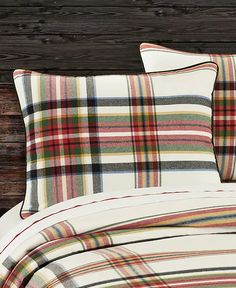 a bed with plaid sheets and pillows on it