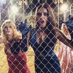 two women behind a chain link fence with their hands in the air and one holding up her hand