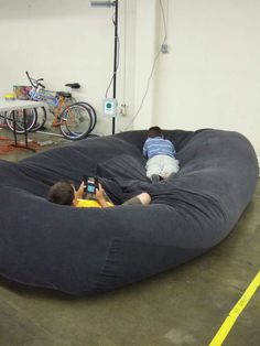 two boys are laying on a bean bag chair