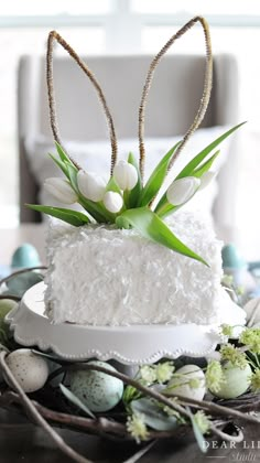 a cake with white frosting and flowers in the shape of an easter bunny's ears