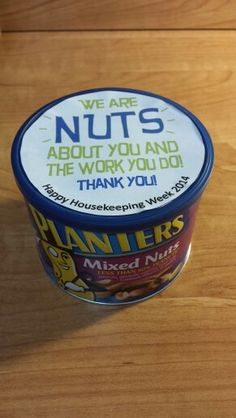 a container of nut butter sitting on top of a wooden table next to a cup of coffee