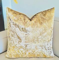 a gold pillow sitting on top of a white couch