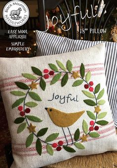 the joyful pillow is on display in front of a christmas tree with berries and leaves