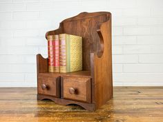 a wooden chair with two books on top of it and a book case in the back