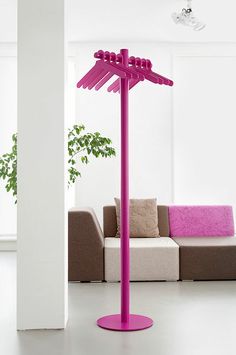 a purple pole in the middle of a living room next to a couch and potted plant