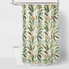 a shower curtain with green and yellow leaves on it