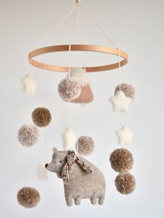 a baby mobile with pom - poms hanging from it's sides and a teddy bear on the other side