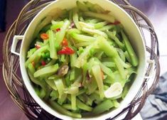 a white bowl filled with green vegetables on top of a table