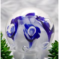 a blue and white glass sculpture sitting on top of a table next to pine cones