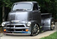 an old truck is parked on the side of the road in front of some trees