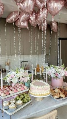 a table topped with lots of desserts and balloons hanging from the ceiling above it