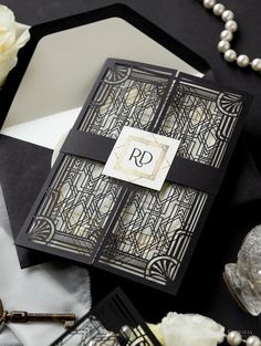 a black and white wedding card with a monogrammed initials on it, surrounded by pearls