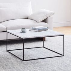 a living room with a white couch and coffee table on the rug in front of it