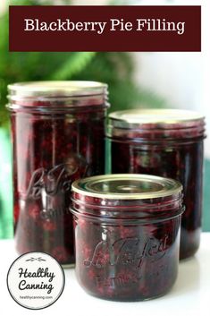 three jars filled with blackberry pie filling sitting on top of a table