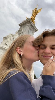 two people kissing each other in front of a statue