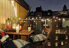 an outdoor patio with lights and furniture on the roof top deck, overlooking cityscape at night