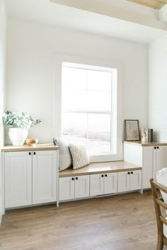 a room with white walls and wooden flooring has a window seat on the far side