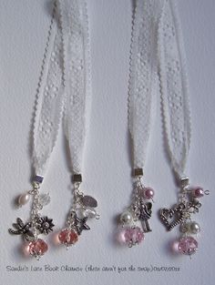 three necklaces with charms attached to them on a white surface, one is pink and the other is silver