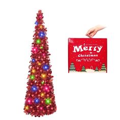 a red christmas tree with lights and a hand holding a merry book next to it