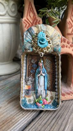 an image of the immaculate mary in a frame on a table next to potted plants