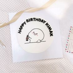 a white birthday cake with a cartoon character on it and a brown ribbon around the edge