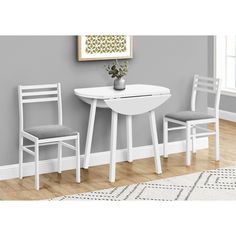 a white table and two chairs in front of a gray wall with a potted plant on it