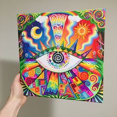 a person holding up a painting with an eye on it