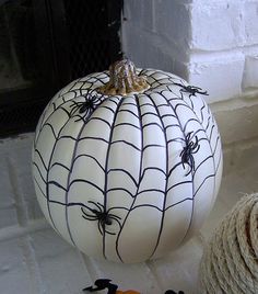 two pumpkins with spider web designs on them sitting next to twine rope balls