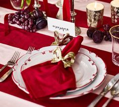 a red and white table setting with place settings, silverware, napkins, and wine glasses