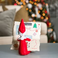 the elf is sitting in front of the christmas tree with his paper bag on it's head