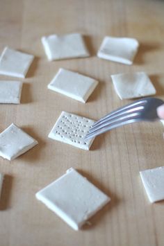 a fork is being used to cut up small squares of white cheese on a cutting board