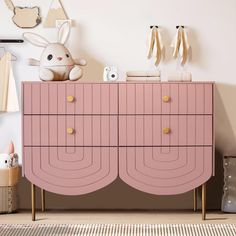 a pink dresser with gold handles in a child's room