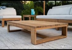 a wooden coffee table sitting on top of a white tile floor next to two couches