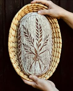 two hands holding a round bread basket with wheat design on the front, and another person's hand reaching for it