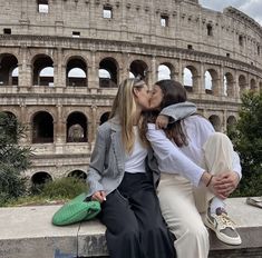 two women kissing each other in front of the colossion