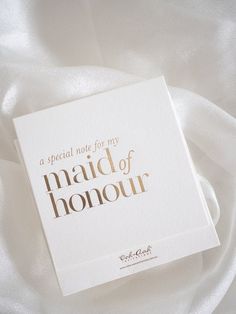 a special note for my maid of honour is laying on a white satin sheet