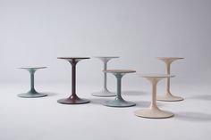 four different colored vases sitting next to each other on a white surface with no one around them