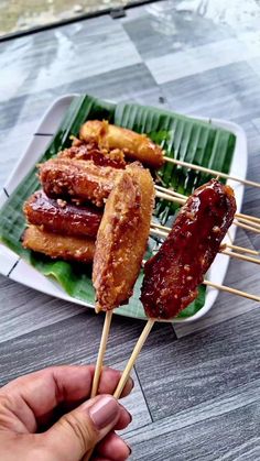 a person is holding some food on a stick with toothpicks in their hand