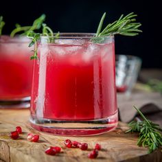 two glasses filled with red liquid and garnished with rosemary