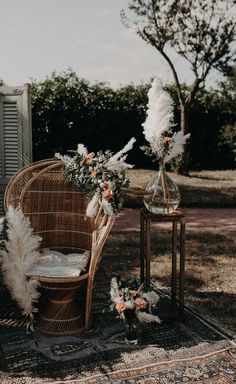 a wicker chair sitting on top of a rug next to a vase filled with flowers