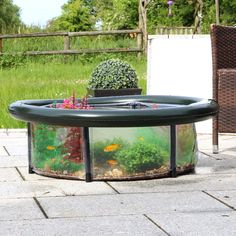 a fish tank sitting on top of a patio next to a table with flowers and plants in it