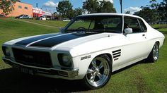 a white and black muscle car parked in the grass