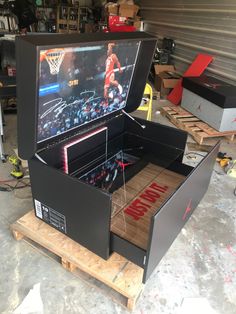 an open box with a basketball game on it in a garage area next to other boxes and tools