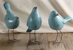 three small blue birds are standing next to each other