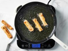 three pieces of fish frying in a skillet on top of a kitchen scale