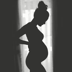 a pregnant woman standing in front of a window