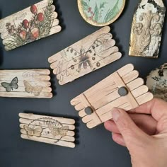 a person is holding up some wooden clothes pins with butterflies and flowers painted on them