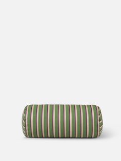 a green and white striped pillow sitting on top of a gray floor next to a wall